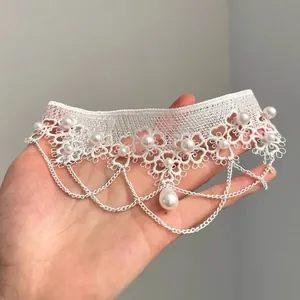 Gros plan d'un ras-du-cou en dentelle blanche rétro avec perles et pampilles de chaînes