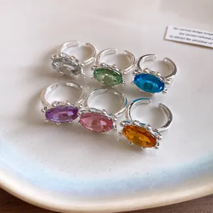 Detailansicht von sechs farbenfrohen Ringen mit ovalen Edelsteinen und offenen Bändern.