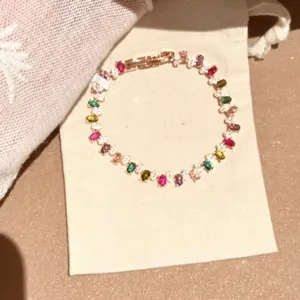 Detail eines bunten Regenbogen-Edelsteinarmbands auf einem beigen Stoffbeutel