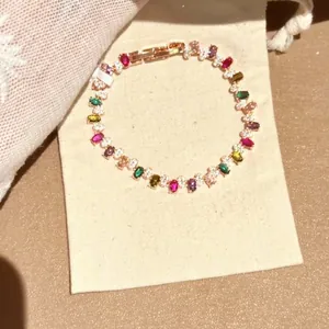 Detailansicht eines eleganten Regenbogen-Armbands mit bunten Steinen auf Stoffbeutel