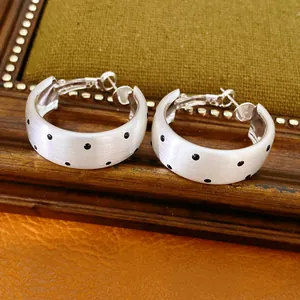 Vue détaillée des boucles d'oreilles en argent brossé avec motif à pois noirs pour femmes