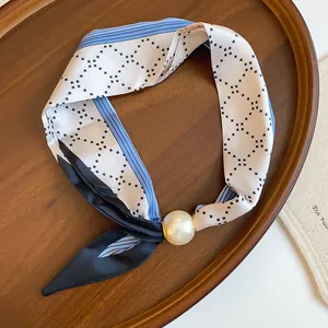 Nahaufnahme eines Seidenschal-Chokers mit Perlenanhänger und geometrischem Musterdesign