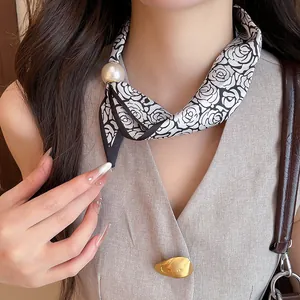 Detailansicht eines eleganten Seidenschal-Chokers mit großem Perlenanhänger und Rosenmuster-Design