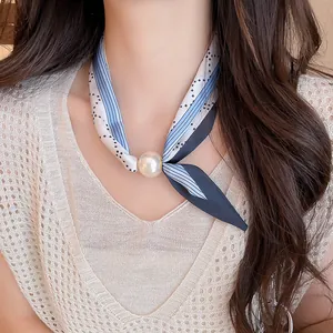 Nahaufnahme einer eleganten Seidenschal-Halskette mit großer weißer Perle