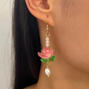 Macro detail of elegant pink resin lotus and pearl drop earring on model's ear