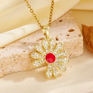 Close-up of elegant gold flower pendant necklace with red center and crystal petals