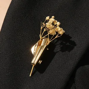 Elegante spilla a bouquet dorata con fiori di gipsofila secchi su un blazer nero