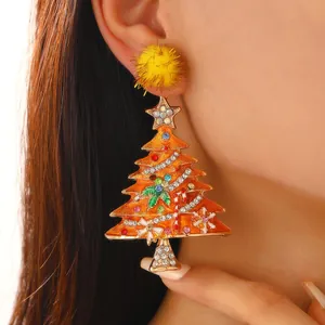 Close-up shot of a festive orange Christmas tree earring with colorful rhinestones and pom-pom