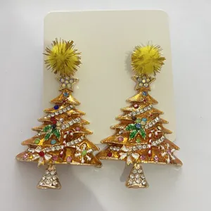 Detailed view of festive rhinestone Christmas tree stud earrings with yellow pom pom tops.