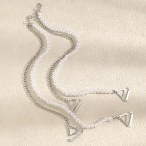 Detailed view of elegant pearl and silver-toned chain bra straps with triangular hooks.