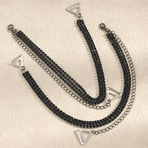 Detailed view of black rhinestone decorative bra straps with silver triangular hooks