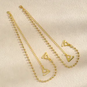Detailed view of gold rhinestone bra straps with triangular hooks on textured background