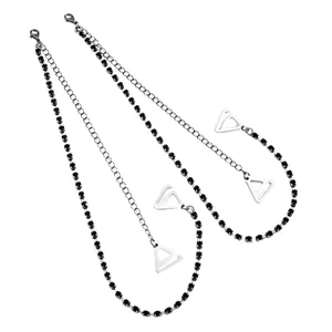 Detailed view of decorative bra straps with black rhinestones and silver metal chains.