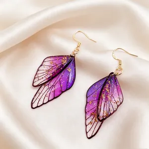 Elegantes pendientes de ala de mariposa en degradado púrpura con detalles dorados.
