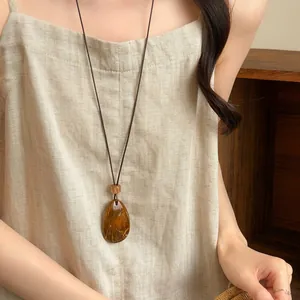 Vintage ketting in etnische stijl met amberkleurige hars hanger en bruin leren koord.