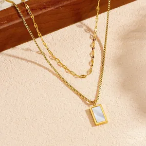Dettaglio di collana a doppio strato placcata oro con pendente rettangolare in madreperla.