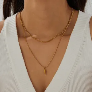 Dettaglio di una collana a doppio strato placcata oro con un ciondolo geometrico a forma di cono
