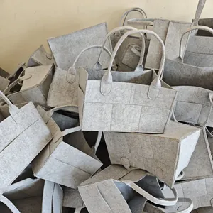 Macro detail view of multiple grey felt storage bags piled up in a warehouse setting
