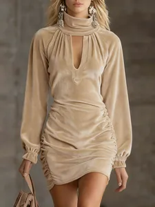 Close-up of elegant beige ruched velvet mini dress with high neck and V-cutout details.