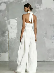 Elegant white backless halter neck wide-leg jumpsuit featuring a bow tie detail at the back