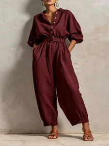 Elegant burgundy long-sleeve jumpsuit with V-neck, buttons, and matching waist belt.