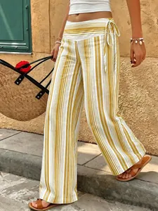 Macro view of yellow and white striped wide-leg trousers with elegant drawstring tie