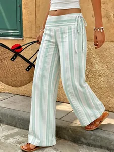 Women's striped wide-leg pants with low waist tie, shown in a relaxed outdoor vacation scene.
