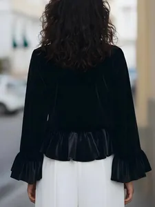 Back view of a black velvet long sleeve top with bell sleeves and ruffled hem