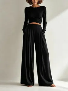 Elegante set nero composto da top a maniche lunghe irregolare e pantaloni larghi