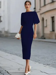 Detail view of an elegant navy blue midi dress worn by a model on a sunny city street
