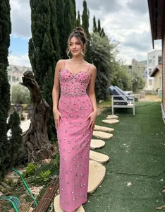 Elegant pink bandage maxi dress with sparkling rhinestones worn by a model in a garden