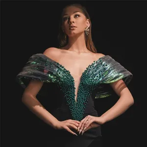 Detailed view of emerald beadwork and ruffled shoulders on black bandage evening gown