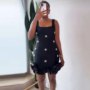 Detailed view of black bandage mini dress featuring silver rhinestone floral appliques