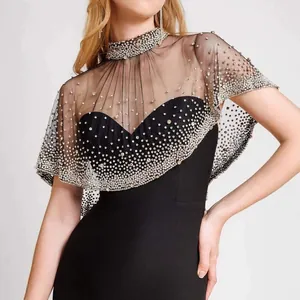 Detailed view of sheer mesh capelet with intricate rhinestone embellishments on black dress