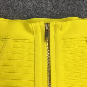 Detail of a yellow bodycon bandage skirt featuring a sturdy gold-tone metal zipper.