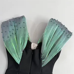Detail of a bandage evening dress with iridescent pleated shoulders and green beadwork