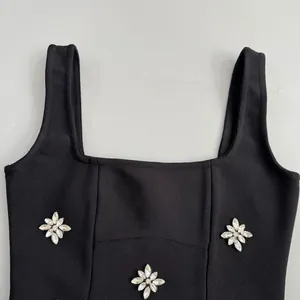 Detailed view of black bandage dress featuring sparkling rhinestone flower appliqués