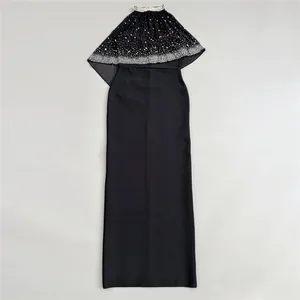 Detailed view of an elegant black evening gown featuring a rhinestone-studded capelet overlay