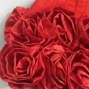 Macro view of the exquisite 3D rose fabric decorations on a vibrant red party dress.