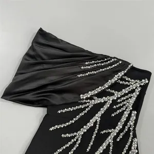Detailed macro view of black bandage evening dress with shimmering rhinestone branch embroidery.