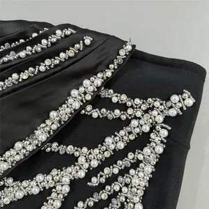 Close-up detail of black bandage evening dress with intricate rhinestone and pearl embroidery