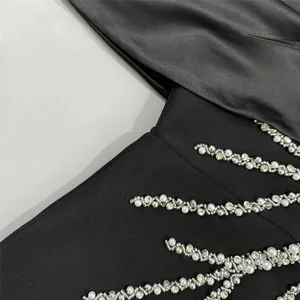 Close-up detail of black bandage dress with sparkling rhinestones and white pearls.