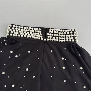 Close-up of black mesh evening dress featuring elegant pearl and rhinestone detailing.