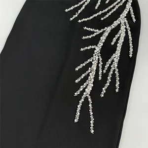 Close-up detail of silver rhinestone and pearl branch embellishment on a black bandage dress
