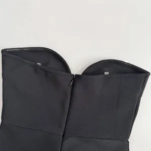 Detail view showing the back invisible zipper and fabric texture of a black bandage dress.