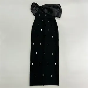 Detail view of stylish black bandage dress featuring large bow and rhinestone embellishments
