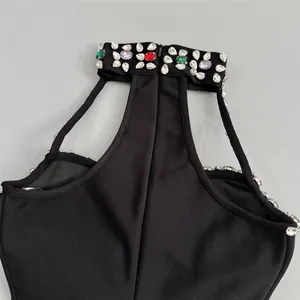 Primer plano del cuello de un vestido bandage negro con pedrería de colores