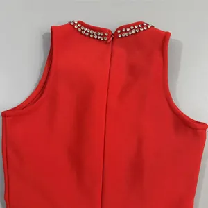 Detailed view of crystal rhinestone collar and back zipper on red bandage evening dress.