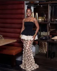 Elegant black strapless evening dress featuring cream ruffled waist and layered polka dot skirt