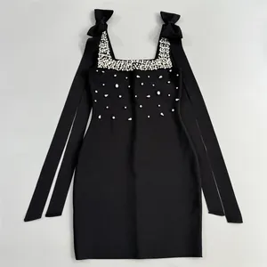 Détail de robe bandage noire avec ornements en strass et nœuds élégants sur les épaules